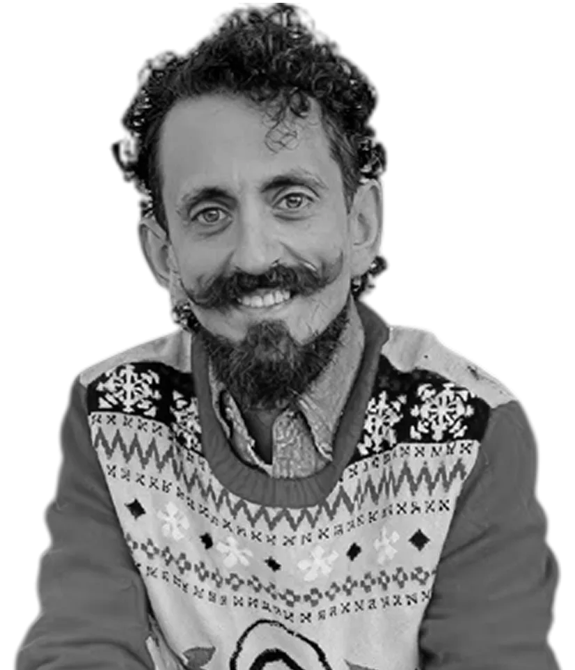 Man with curly hair and a beard wearing a patterned sweater.